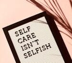Letter board displaying 'Self Care Isn't Selfish' with artistic shadow on pink background.
